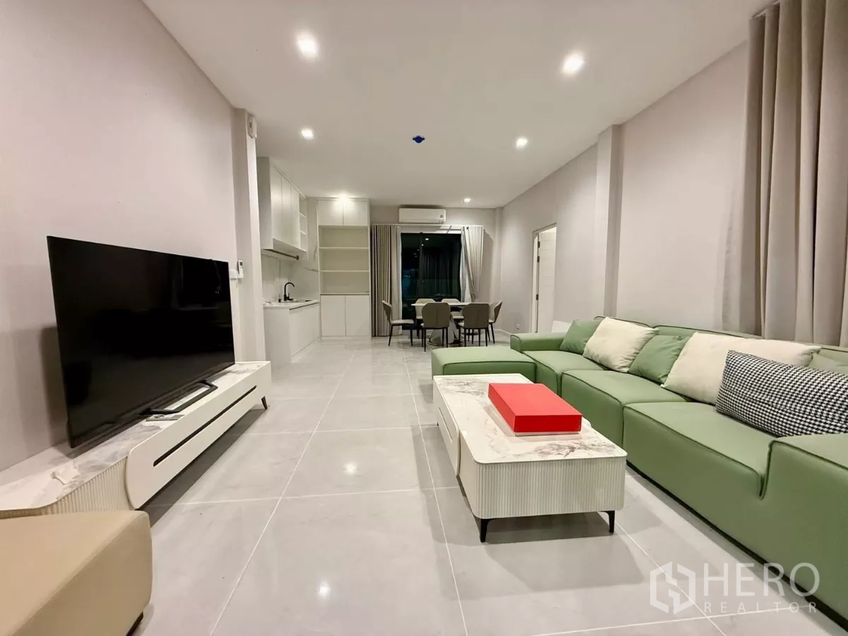独立式住宅 出租在Bang Phli, Samut Prakan - 明亮的客厅，绿色转角沙发、电视柜与筒灯。