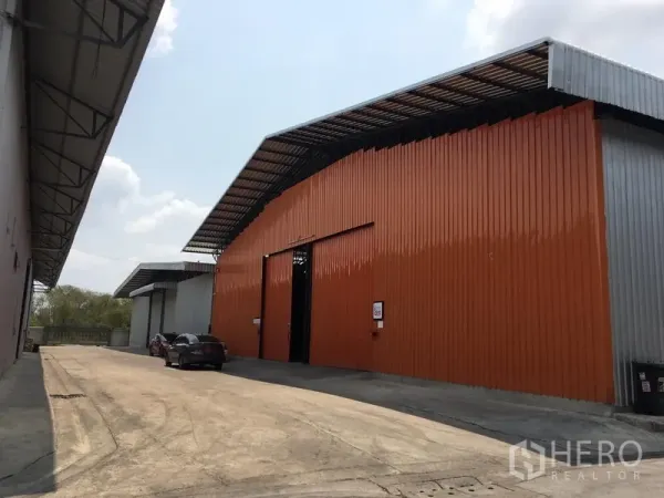 货栈 出租在Bang Kapi, Bangkok - 橙灰色金属外墙的仓库外观，配有宽阔车道，位于 Bang Kapi。