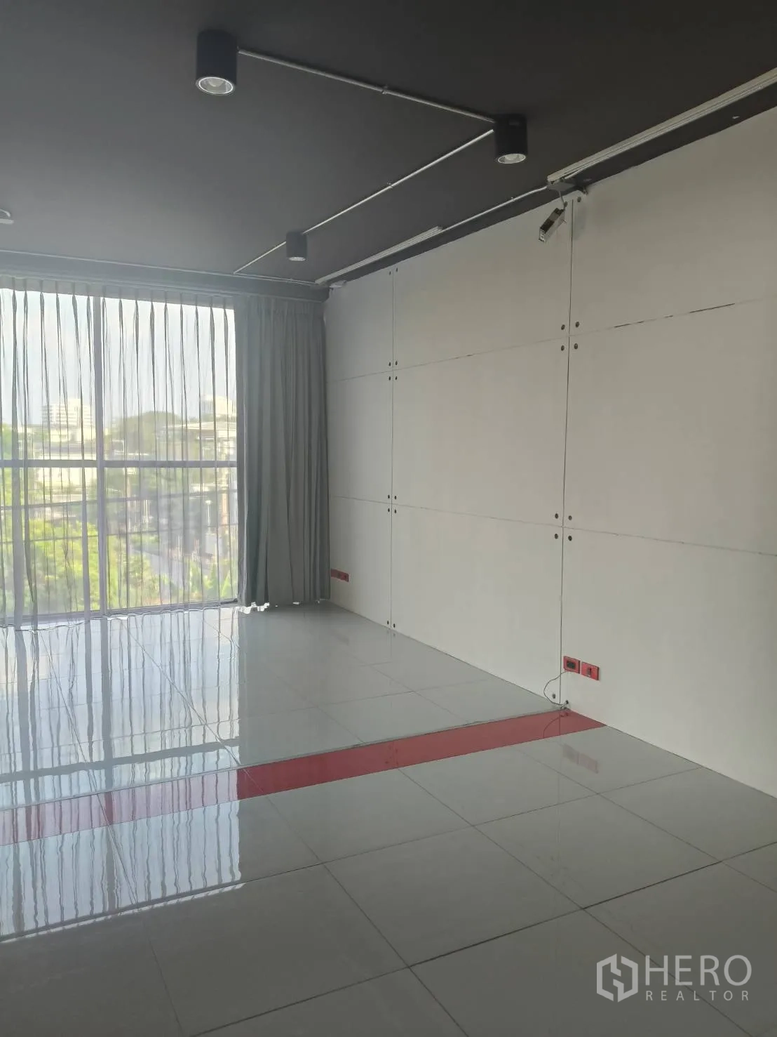 办公空间 出租在Khlong Toei, Bangkok - 开放空间一角，设大窗、轨道灯与白色装饰墙板。