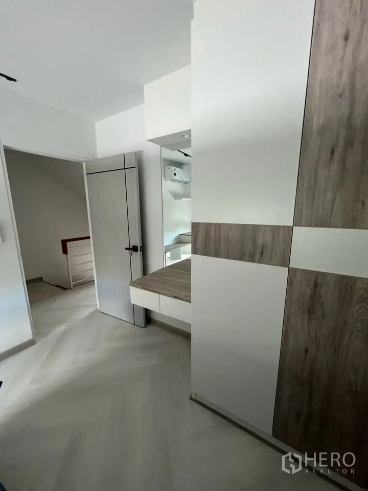 联排别墅 for rent in Prawet, Bangkok - 卧室走廊，内置衣柜、梳妆台和浅色人字拼地板。