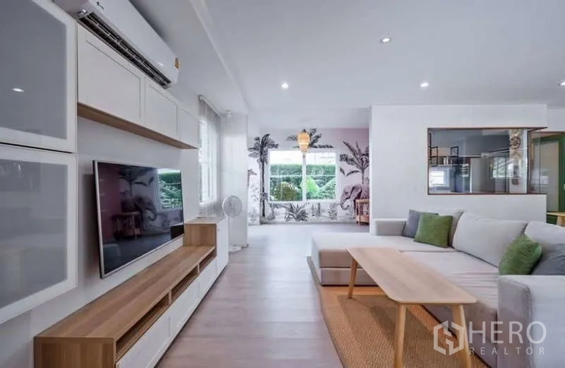 独立式住宅 出租在Prawet, Bangkok - 开放式客餐厅，大型沙发、特色墙面与花园景观。