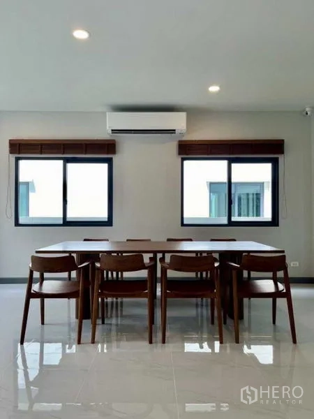 Detached House for rent in Bang Phli, Samut Prakan - Bright dining area with wooden table, eight chairs, and twin windows with air conditioning.