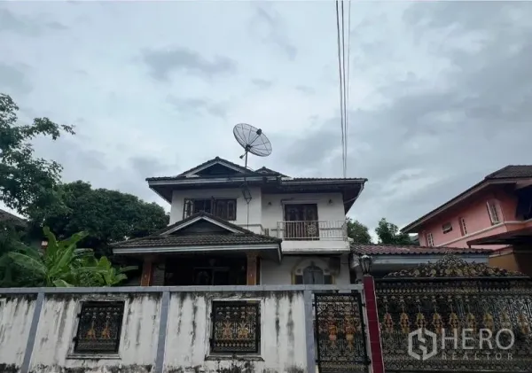 独立式住宅 出售在Phra Khanong, Bangkok - 邦卡区两层独栋别墅外观，带阳台、坡屋顶和精美前院铁门。