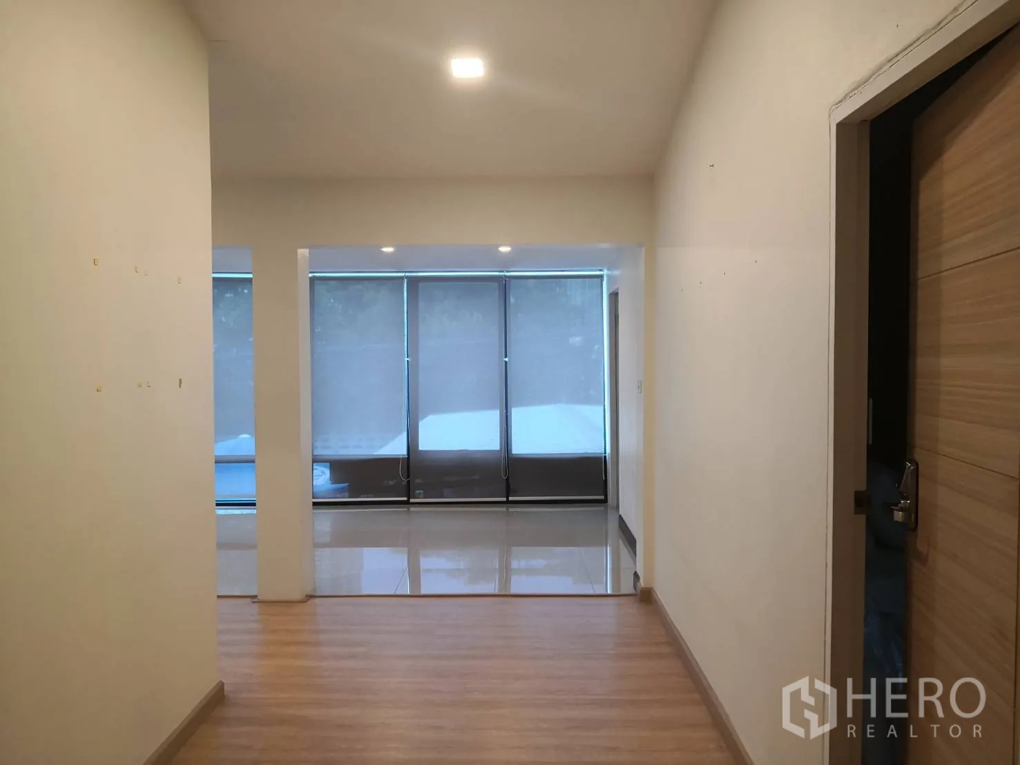 Detached House for rent in Watthana, Bangkok - Entrance hall with wood flooring leading to a bright living area with large windows and roller blinds.