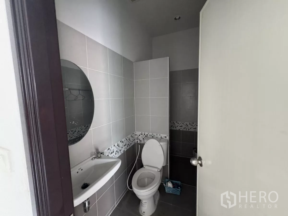 Factory for rent in Phra Samut Chedi, Samut Prakan - Clean tiled restroom with toilet, basin and mirror.