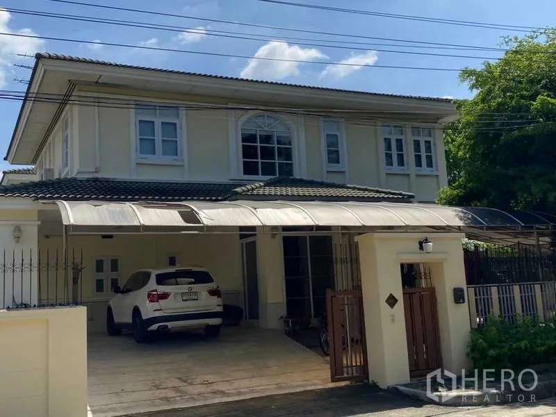Detached House for rent in Prawet, Bangkok - Front elevation of the home with driveway parking under a canopy roof.