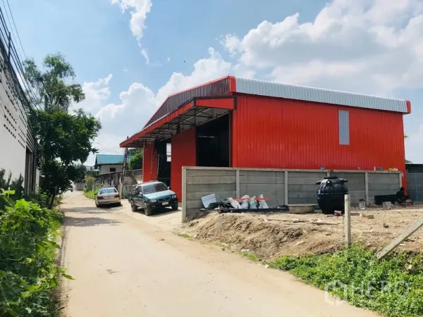 货栈 出租在Bang Kapi, Bangkok - 红色钢板外墙仓库外观，双坡屋顶，临路可停车。