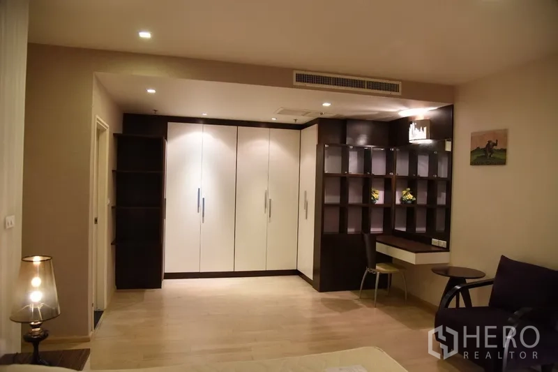 Condominium for rent in Khlong Toei, Bangkok - Bedroom corner with full-height built-in wardrobes, open shelving and a study nook.