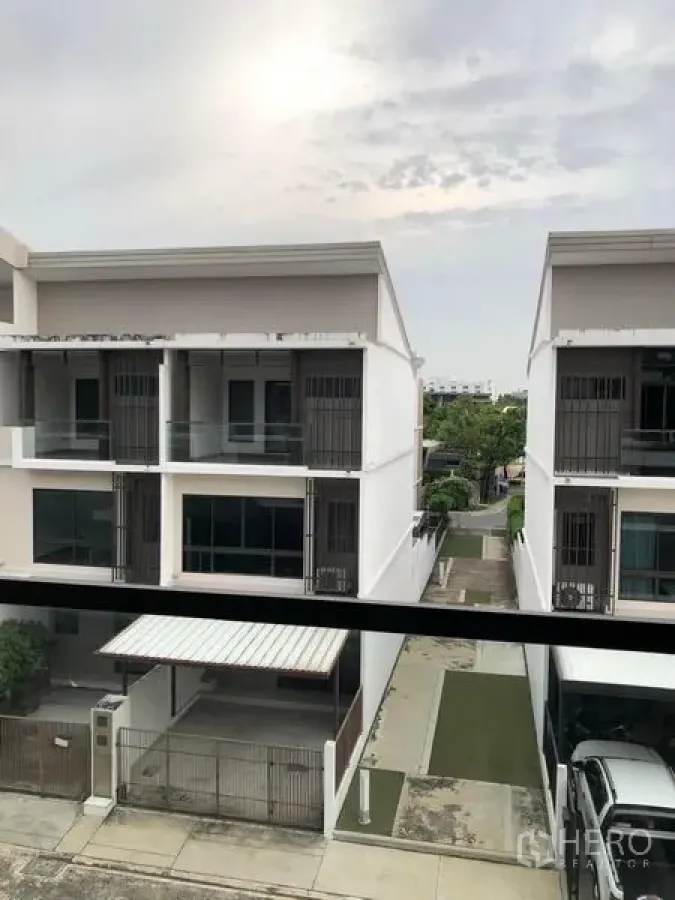 Townhouse for rent in Lat Phrao, Bangkok - View of contemporary three-storey townhouses with balconies and carports on a quiet lane.