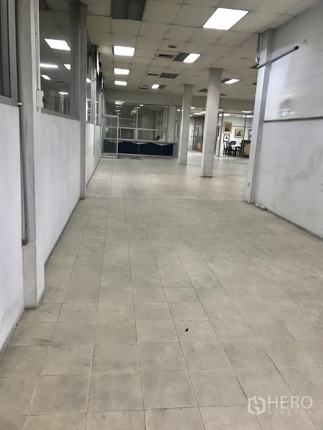 โกดัง for rent in Phra Khanong, Bangkok - โถงทำงานยาวปูพื้นกระเบื้อง มีเสาและไฟเพดาน พร้อมผนังกระจกกั้นห้อง