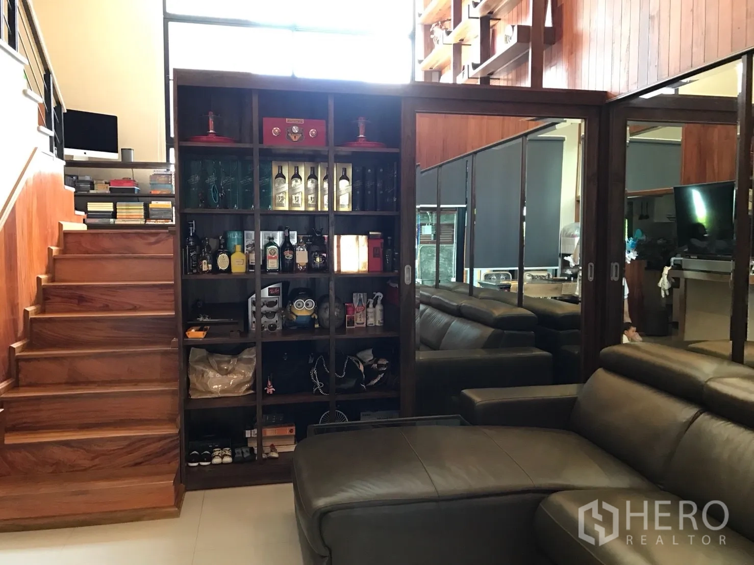 Townhouse for sale in Suan Luang, Bangkok - Living area with wooden staircase, built‑in shelving and mirrored cabinets with a leather sofa