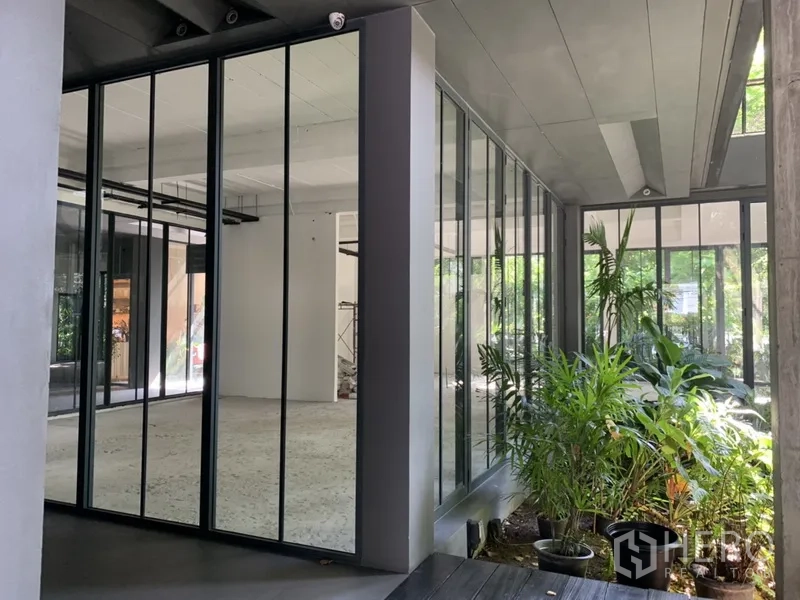 Office Space for rent in Khlong Toei, Bangkok - Covered entry to the office with full-height glass walls and potted plants.