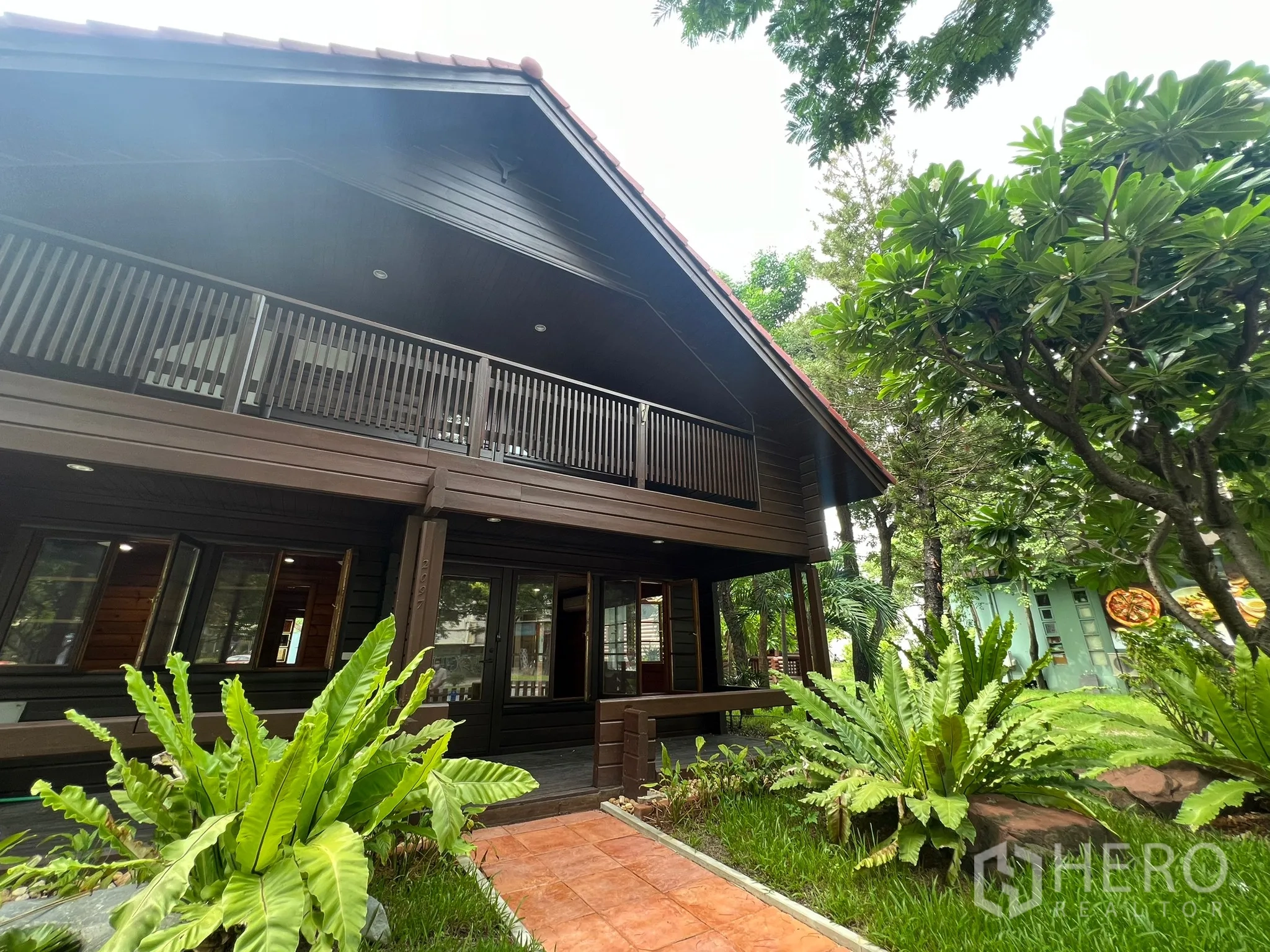 带办公室的家 出租在Suan Luang, Bangkok - 两层木质家用办公楼，带阳台、砖路与花园树木。