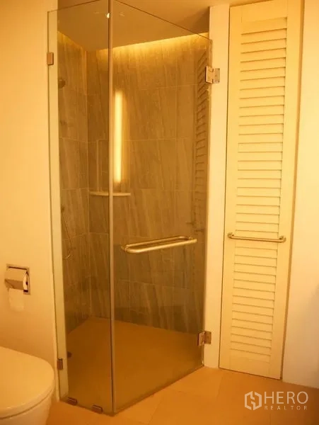 Condominium for rent in Khlong Toei, Bangkok - Modern bathroom with glass-enclosed shower and warm lighting.