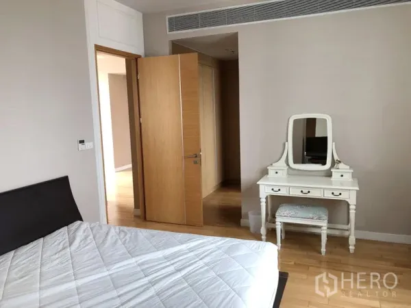 Condominium for rent in Khlong Toei, Bangkok - Calm bedroom with wood floors, a bed and a vintage white dressing table.