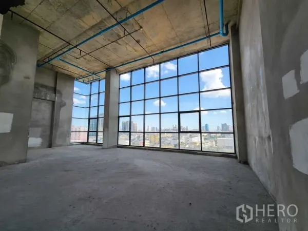 Retail Space for rent in Sathon, Bangkok - Open-plan corner unit with exposed ceiling and curtain-wall windows facing the Bangkok skyline.