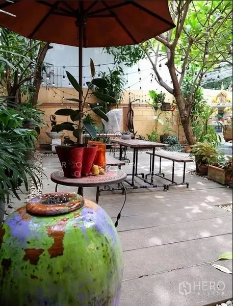 บ้าน ให้เช่าในWatthana, Bangkok - ลานสวนร่มรื่น มีร่ม โต๊ะสไตล์ลอฟท์ และกระถางต้นไม้ข้างรั้วไม้