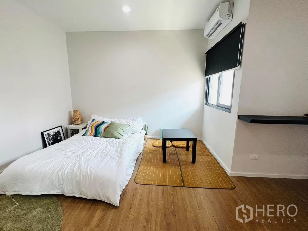 Detached House for rent in Saphan Sung, Bangkok - Minimalist bedroom with low bed, floor seating and wood flooring.