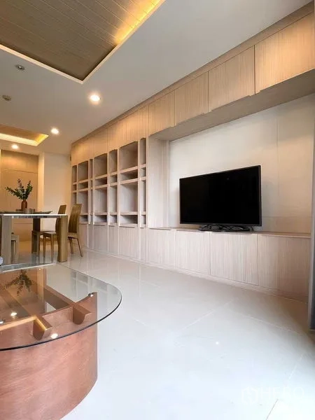 Condominium for rent - Open-plan living area with TV, extensive built-in shelving and glossy tile floors.