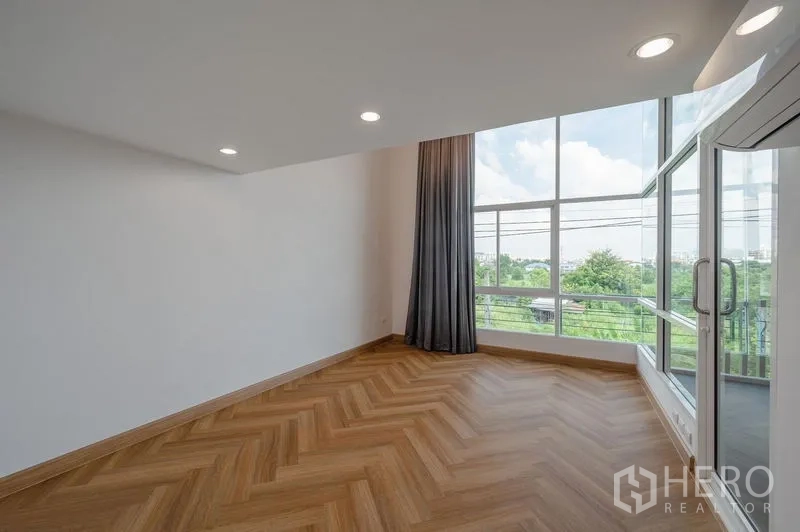 联排别墅 出售在Lat Phrao, Bangkok - 转角房间采光充足，鱼骨拼木地板与落地窗对望绿景。