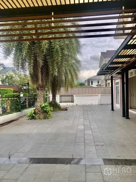 独立式住宅 出售在Lat Krabang, Bangkok - 庭院一侧有棕榈树并设遮阳步道。