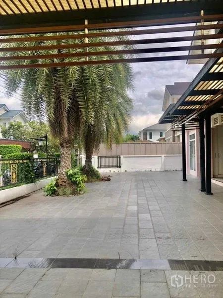 独立式住宅 出售在Lat Krabang, Bangkok - 庭院一侧有棕榈树并设遮阳步道。