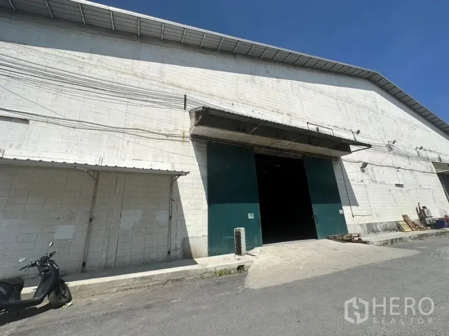 Warehouse for rent in Suan Luang, Bangkok - Warehouse exterior in Suan Luang Bangkok with large green loading door and canopy.