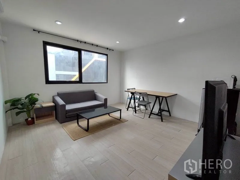 Home Office for rent - Minimalist lounge and office zone with sofa, large window, writing desk and chairs.