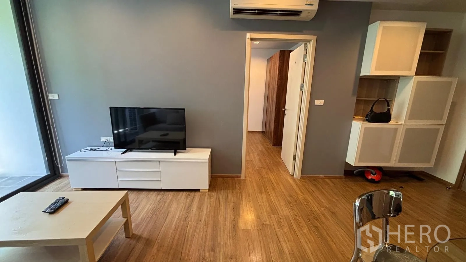 公寓 for rent or sale in Watthana, Bangkok - 起居区设电视柜与壁挂空调，门通往卧室。