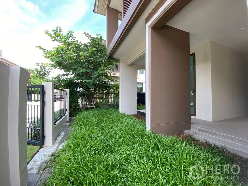 Detached House for rent in Bang Kapi, Bangkok - Side garden strip with lush grass and metal fence along the house.