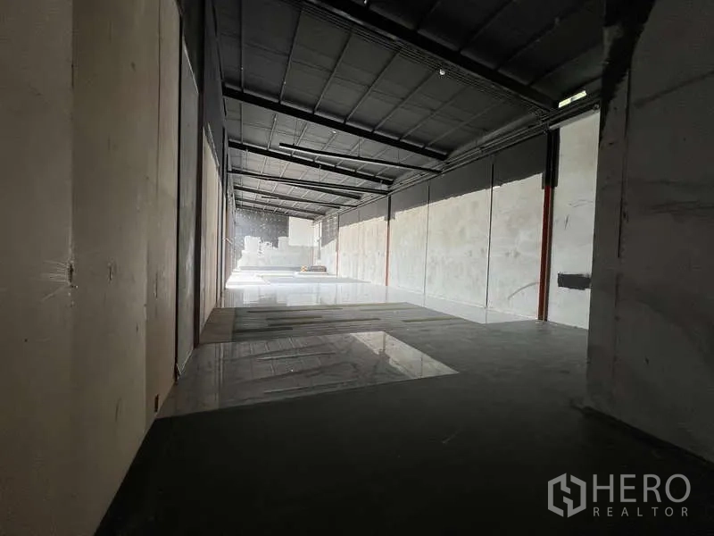 零售空间 出租在Bang Na, Bangkok - 长进深的毛坯零售大厅，外露钢结构屋顶与瓷砖地面，布局灵活。