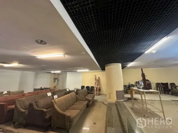 Retail Space for rent - Interior with long sofa rows beneath a black grid ceiling and a central column.