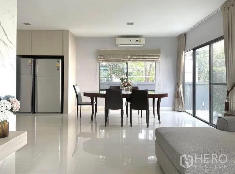 Detached House for rent in Prawet, Bangkok - Dining space with six‑seat table, air conditioner and sliding glass doors opening to the patio and garden.
