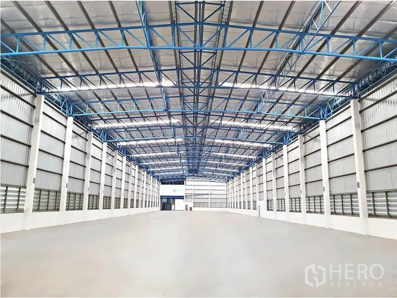 货栈 出租在Lat Krabang, Bangkok - 仓库内部为大跨无柱空间，隔热高屋顶与蓝色钢桁架，抛光混凝土地面。