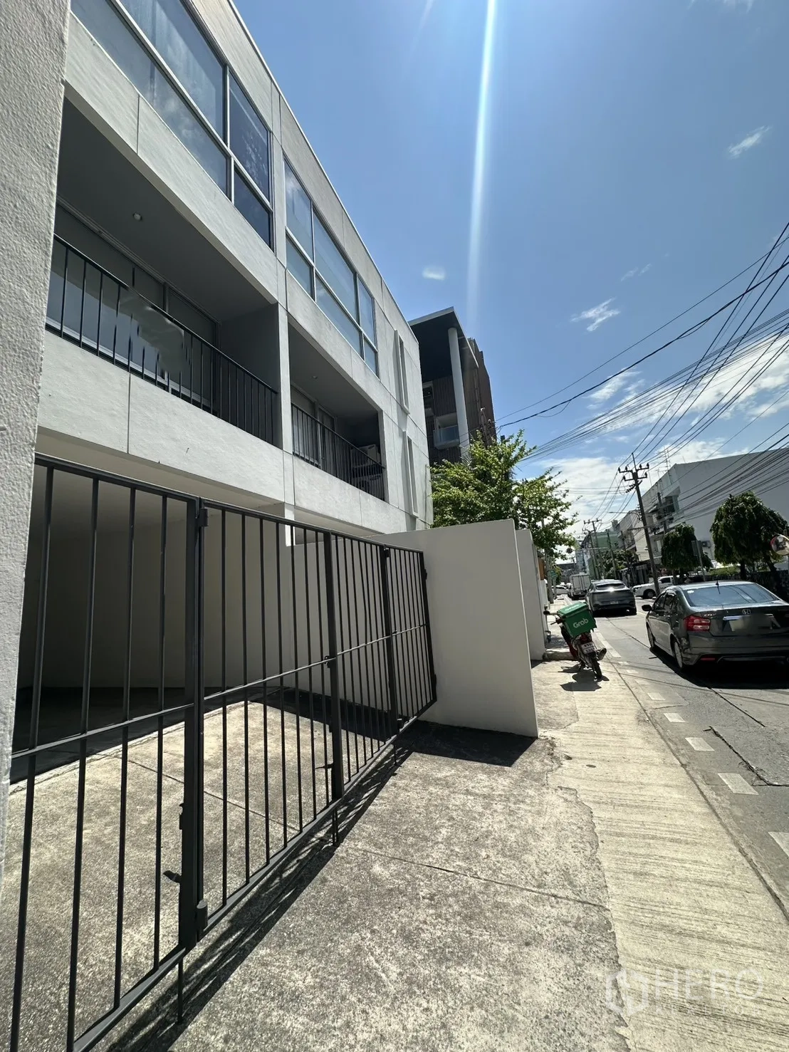 โฮมออฟฟิศ for rent in Phra Khanong, Bangkok - มุมมองริมถนนของอาคารและประตูเลื่อนในวันที่แดดจ้า.