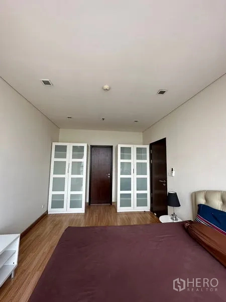 公寓 出售在Watthana, Bangkok - 卧室配木地板与两组玻璃门衣柜，旁有深色木门。