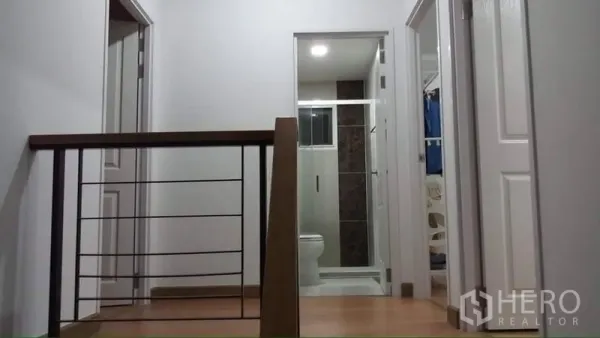 独立式住宅 出租或出售在Prawet, Bangkok - 二层走廊与木扶手，可见浴室与卧室门