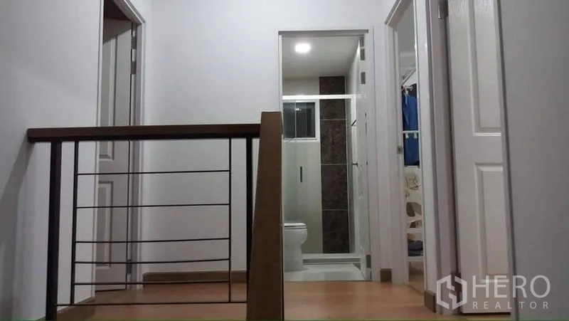 独立式住宅 出租或出售在Prawet, Bangkok - 二层走廊与木扶手，可见浴室与卧室门