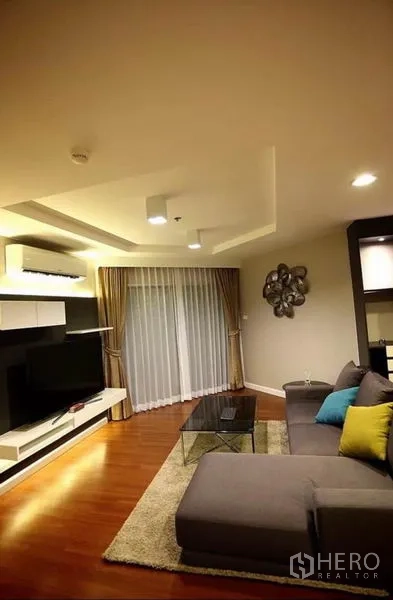 คอนโด ให้เช่าในHuai Khwang, Bangkok - โซนรับแขกพร้อมโซฟาเซกชันนัล พรม โต๊ะกลางกระจก และผ้าม่านเต็มความสูง