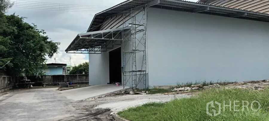 Warehouse for rent in Phra Pradaeng, Samut Prakan - Covered loading bay with steel canopy, entrance ramp, and scaffolding at the front of the warehouse.