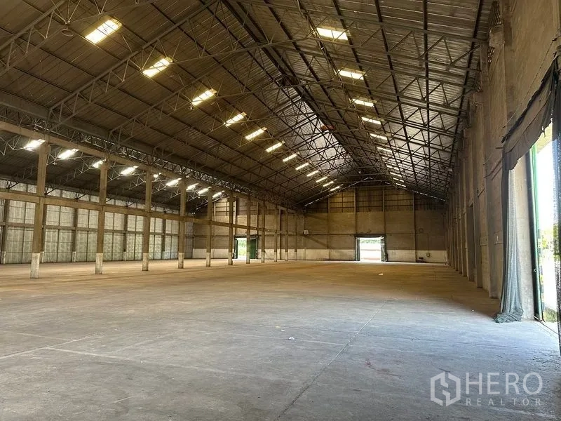 Warehouse for rent in Mueang Pathum Thani, Pathum Thani - Long clear‑span hall with multiple loading doors at both ends and ample natural light.