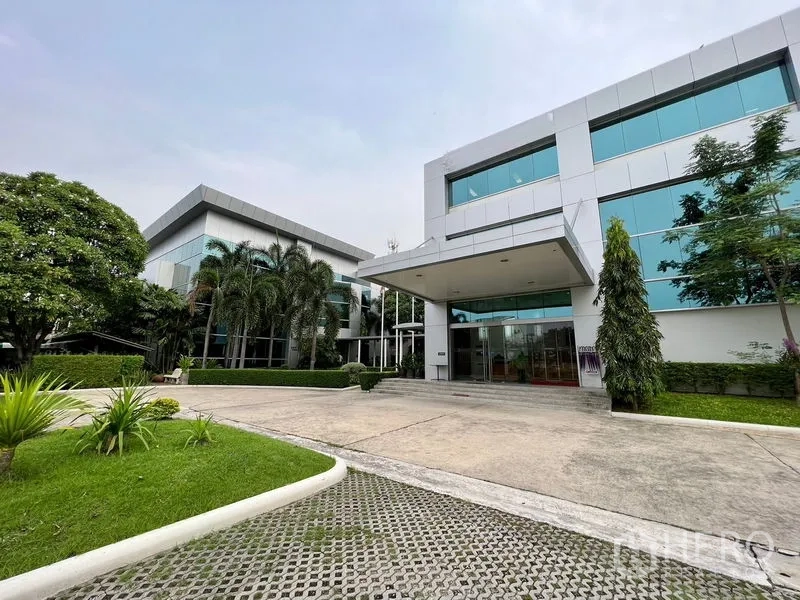 Office Space for rent in Bueng Kum, Bangkok - Modern low-rise office building exterior with reflective glass, landscaped gardens, driveway and covered entrance.