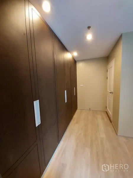 Condominium for rent in Phaya Thai, Bangkok - Hallway featuring full-height built-in wardrobes with warm recessed lighting.