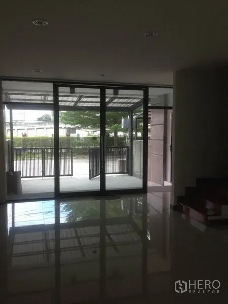 Home Office for rent in Bang Phli, Samut Prakan - Ground-floor interior looking through large glass sliding doors to the gated parking area.