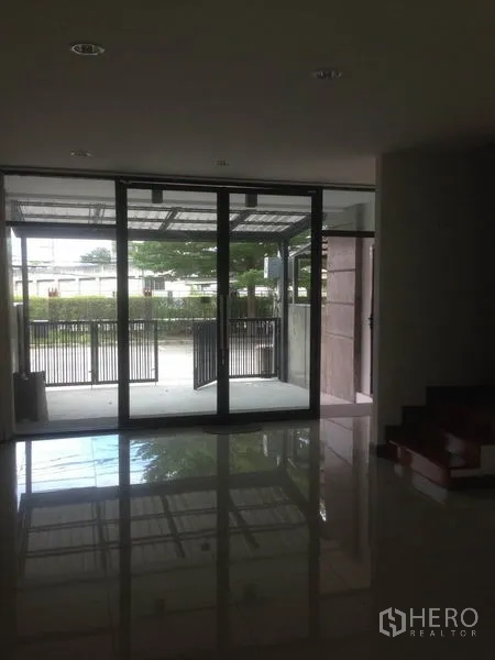Home Office for rent in Bang Phli, Samut Prakan - Ground-floor interior looking through large glass sliding doors to the gated parking area.