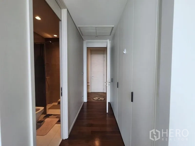 Condominium for sale - Hallway with built-in closets leading toward bedroom and bathroom entrances.