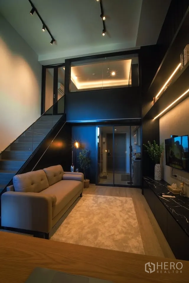 公寓 for rent in Huai Khwang, Bangkok - 复式客厅，挑高空间，楼梯、沙发、玻璃隔断与电视柜一应俱全。