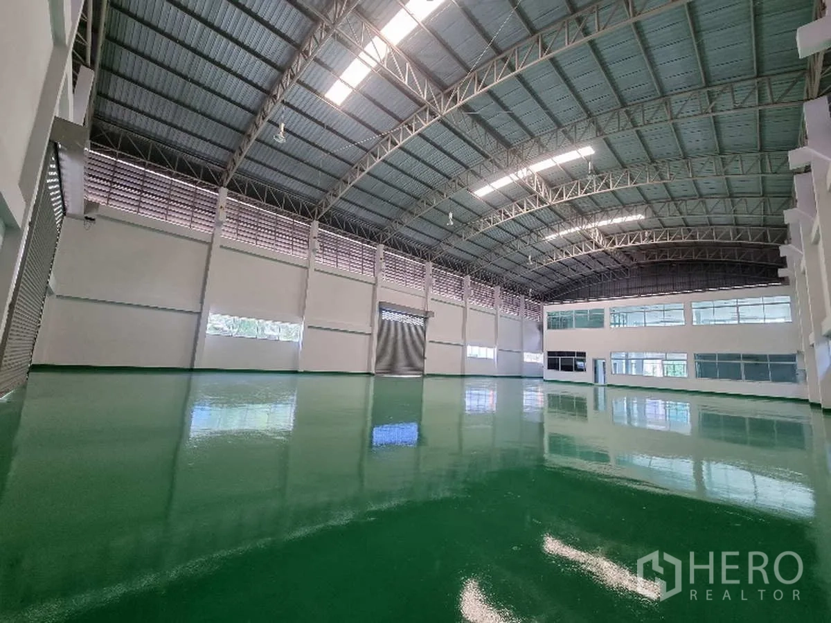 โรงงาน ให้เช่าในSamut Prakan - ภายในคลังสินค้าโล่ง มีสกายไลต์ ประตูม้วนหลายจุด และหน้าต่างสำนักงาน