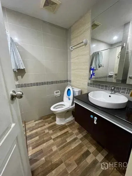 Condominium for rent - Tiled bathroom with vanity sink, large mirror and toilet.