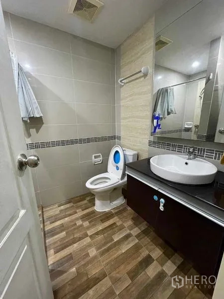Condominium for rent - Tiled bathroom with vanity sink, large mirror and toilet.